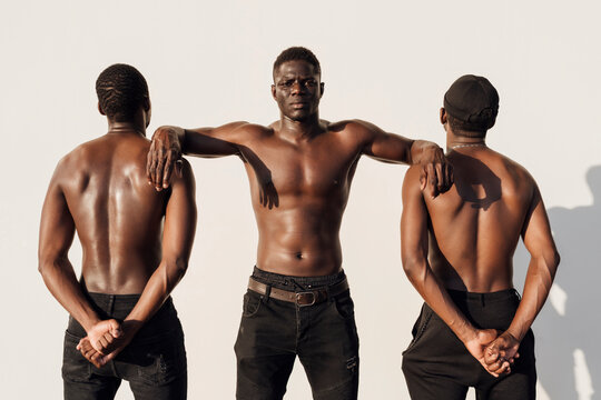 Black man leaning on friends, crossing hands behind their backs