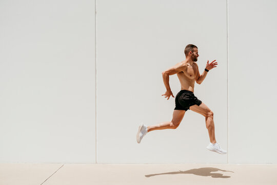 Barechested male athlete jumping at a wall
