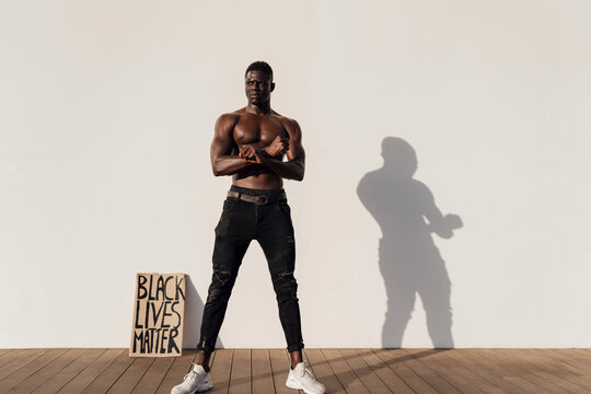 Black Man Crossing Hands With Black Lives Matter Sign Leaninig On Wall