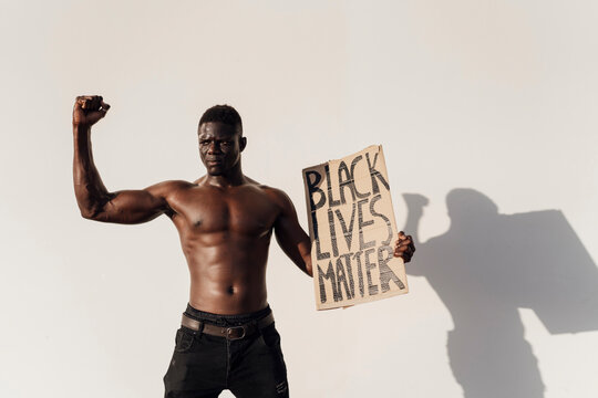 Black man raising fist, holding Black Lives Matter sign