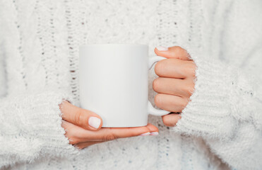 White mug mockup. Girl is holding white 11 oz ceramic cup in hands, wears cozy knitted sweater....