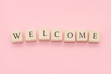 The word WELCOME is made of wooden cubes on a yellow background.