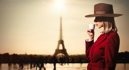 Fototapeta na wymiar girl in red coat drink a coffee wit hEiffel tower on backgorund