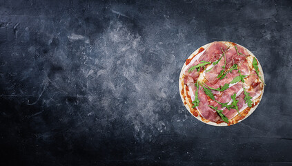 Unbaked pizza with ham on dark background