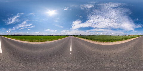Fototapeta premium Full spherical seamless hdri panorama 360 degrees angle view on no traffic asphalt road among fields with cloudy sky in equirectangular projection, VR AR content