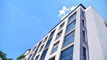 Obraz premium Modern apartment buildings on a sunny day with a blue sky. Facade of a modern apartment building. Glass surface with sunlight.