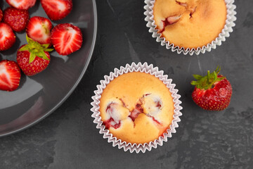 Strawberry muffins with fresh berries on black background, flat lay