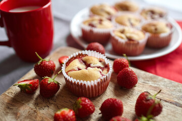 Strawberry muffin with fresh ripe berries over kitchen table background