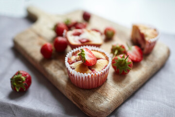 Homemade summer pastry - strawberry muffins on wooden cutting board
