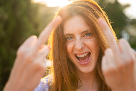 Portrait of laughing redheaded woman giving the finger