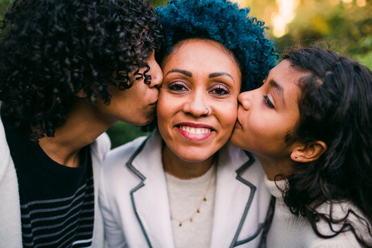 Close-up of loving children kissing on mother's cheeks in park