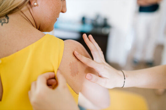 Physiotherapist applying cross tape on patient's shoulder