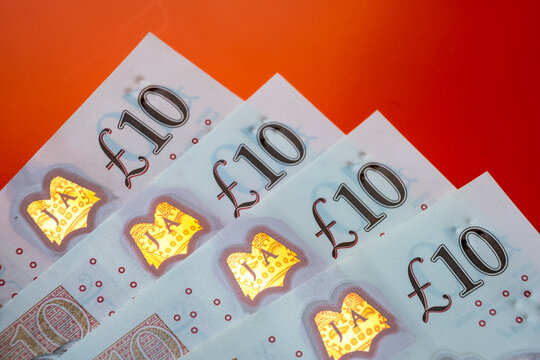 British pound sterling banknotes. Corners of 10 pound notes placed one on top of another on the vivid orage-red background.
