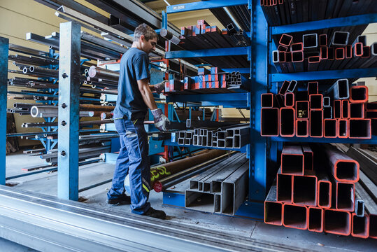 Man working with metal bars on a shelf in a factory