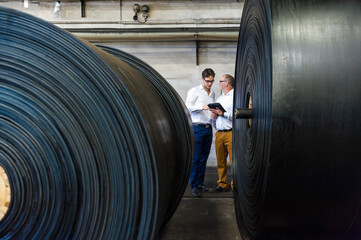 Two businessmen having a meeting in a rubber processing factory