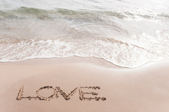 Word 'LOVE' scarified in wet sand at seafront