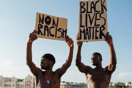 Two men holding Black Lives Matter and ati racism signs in the street