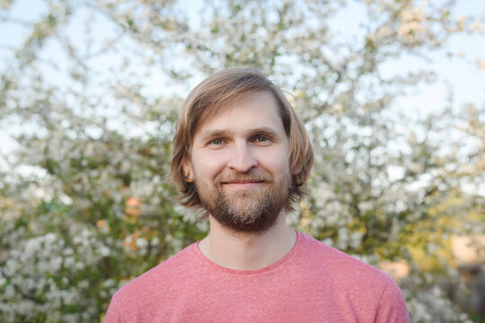 Close-up portrait of smiling bearded man against tree at back yard