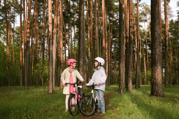 Girl and boy standing with bicycles in forest