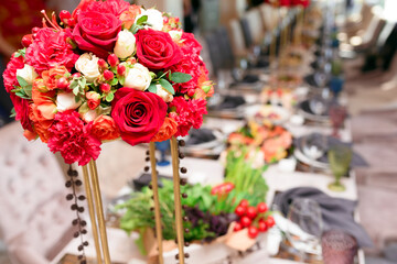 Beautiful table flower bouquet or floral arrangement on a blurry background of a long festive banquet restaurant table