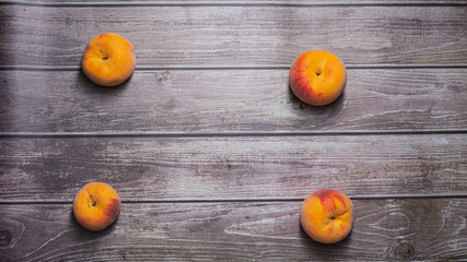 Four tasty peaches fruit in a row on a striped wooden surface