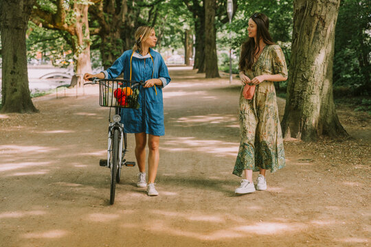 Two Women With Bicycle And Face Mask Walking In Park