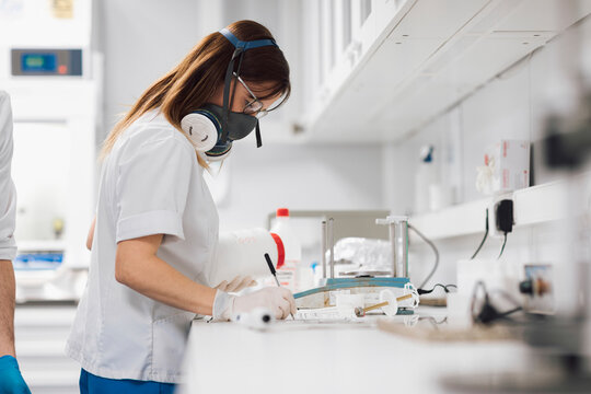 Female doctor writing data by weight scale on desk at laboratory