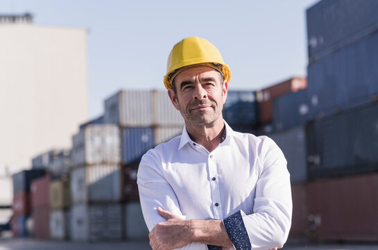 Portrait of businessman wearing safety helmet in front of cargo containers