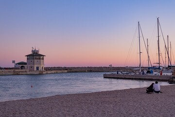 romantic sunset at the port of Ostia, a lighthouse, some boats  and a charming colorful sky at sundown.; maritime panorama that inspires calm and tranquility in a hug of love
