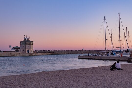 romantic sunset at the port of Ostia, a lighthouse, some boats  and a charming colorful sky at sundown.; maritime panorama that inspires calm and tranquility in a hug of love