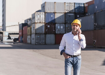 Businessman on the phone wearing safety helmet at industrial site