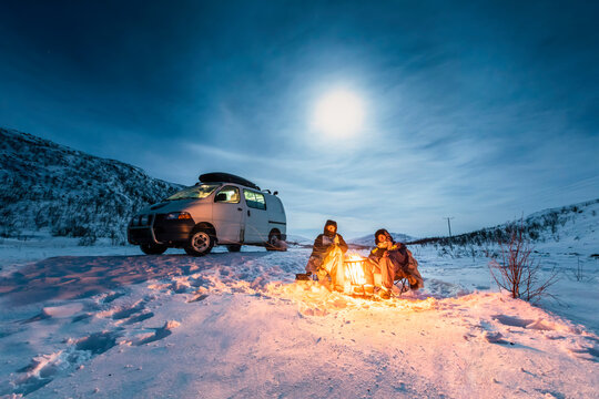 Campers at camp fire in winter landscape in polar night, Kilpisjaervi, Enontekioe, Finland