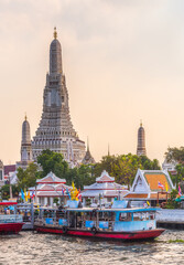 Boats on Chao Phraya River and Wat Arun, The Temple of Dawn, an Important Buddhist Temple and a Famous Tourist Destination in Bangkok Yai District of Bangkok, Thailand.