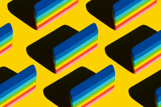 Pattern of rainbow colored erasers against yellow background