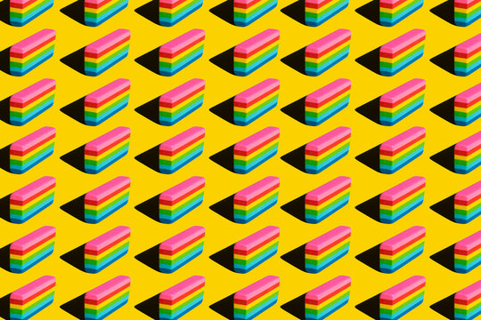 Pattern of rainbow colored erasers against yellow background