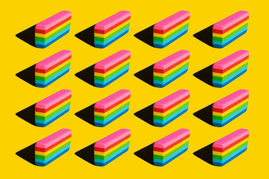 Pattern of rainbow colored erasers against yellow background