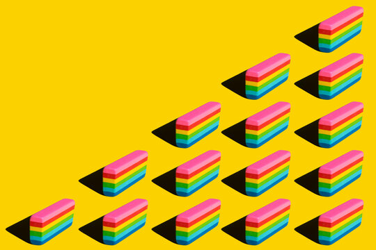Pattern of rainbow colored erasers against yellow background