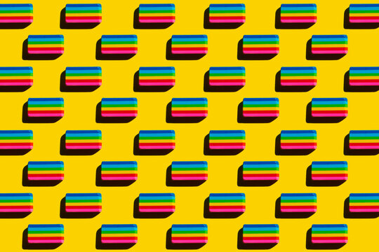 Pattern of rainbow colored erasers against yellow background