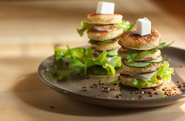 appetizer of mini pancakes, greens and soft cheese on a gray plate with flax seeds, with space