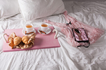 Fototapeta na wymiar breakfast in bed with fruits and pastries on a tray -waffles, croissants, coffe and juice