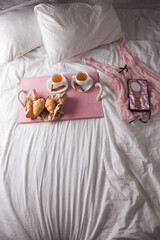 Fototapeta na wymiar breakfast in bed with fruits and pastries on a tray -waffles, croissants, coffe and juice