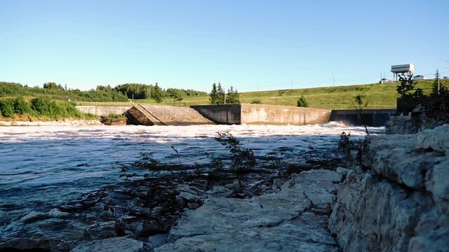 Stream of river water near the dam. The water foams and rushes forward. The camera follows the stream
