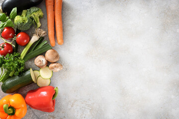 Fototapeta na wymiar Colorful organic vegetables on the side of a light gray surface with large copy space, healthy kitchen background, high angle view from above
