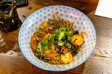 Wok fried shrimp with rice noodles in a plate on the table
