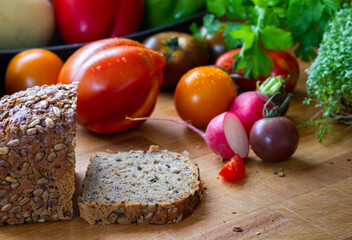 Tomaten Paradeiser Raritäten alte Sorten mit Radieschen auf einem Holzbrett und einer Brotscheibe aufgeschnitten niemand