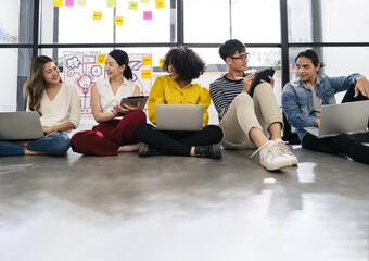 Group of young happy Asian creative business people or hipster student using electronic devices tablet and laptop connection together in modern office. Creative lifestyle young people concept