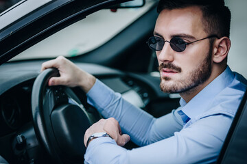 Handsome man with black sunglasses sitting in luxury car posing