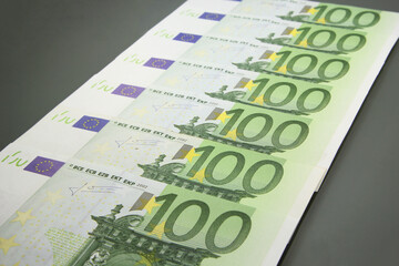 Stack of various one hundred euro bills, one hundred euro cash bills on dark background.