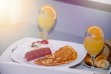a dish of delicious breakfast, two sausages and an omelette with two glasses of orange juice with...