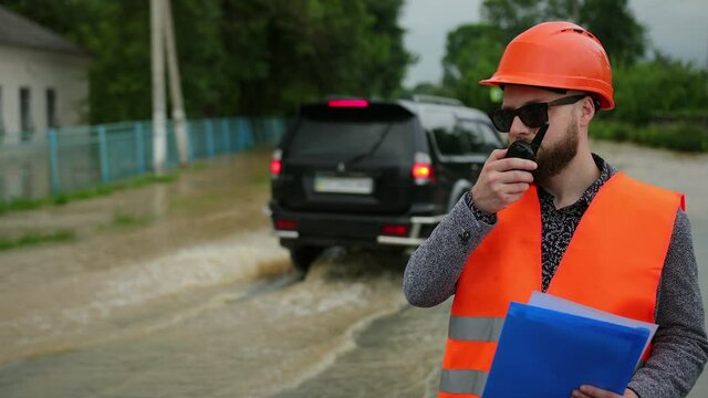 Natural disaster major flooding underwater entire community and neighborhood flooded. Homes, houses overflowing with water, home insurance needed. Engineer on the walkie talkie using